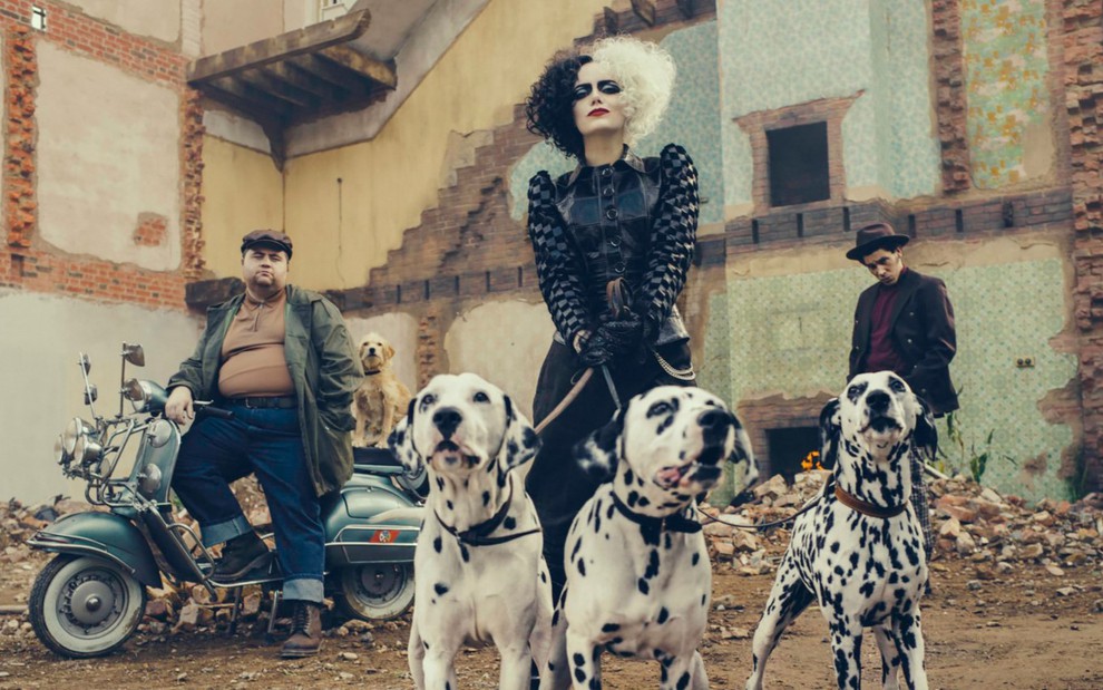 emma stone como cruella segurando seus cães pela coleira