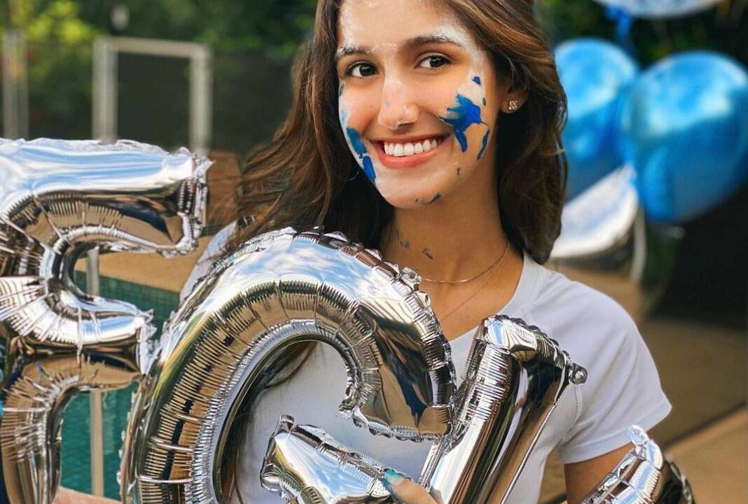 Gabriela Ferraz Ricci, a "Gabi da AE4", posa com tinta azul no rosto segurando as letras FGV.