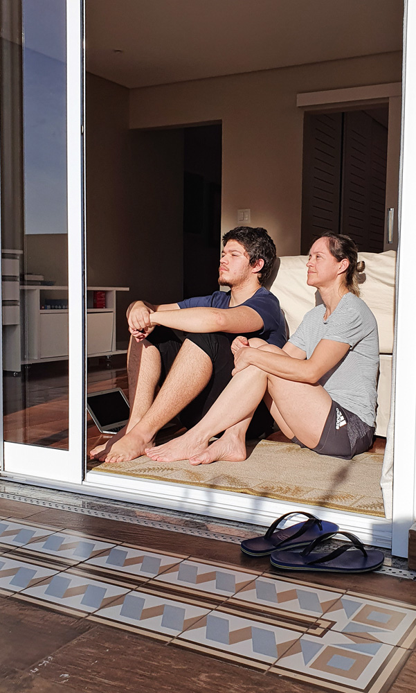 guilherme e a m&atilde;e sentados no ch&atilde;o olhando para o horizonte