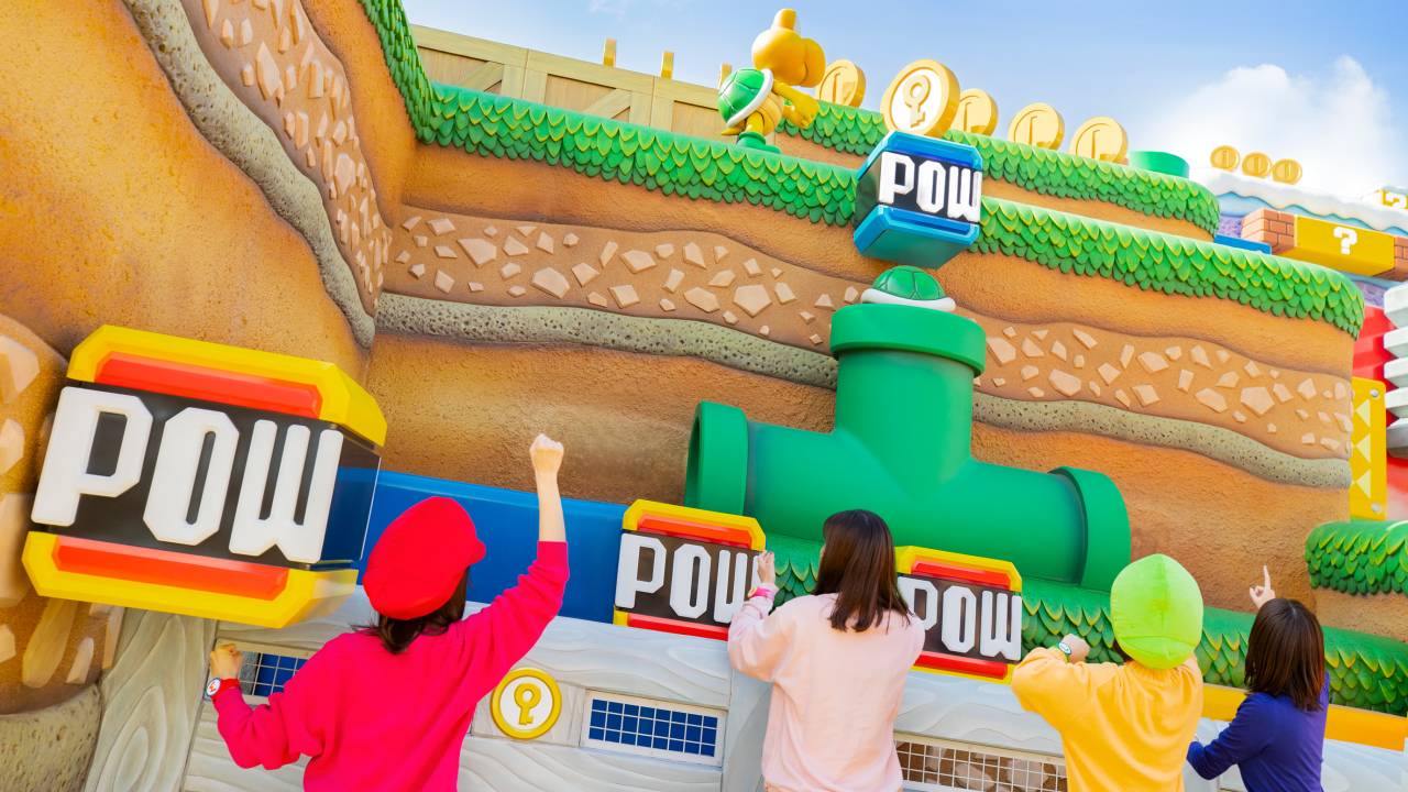 Pessoas brincando no Super Nintendo World em cenário com elementos do mundo do Mario