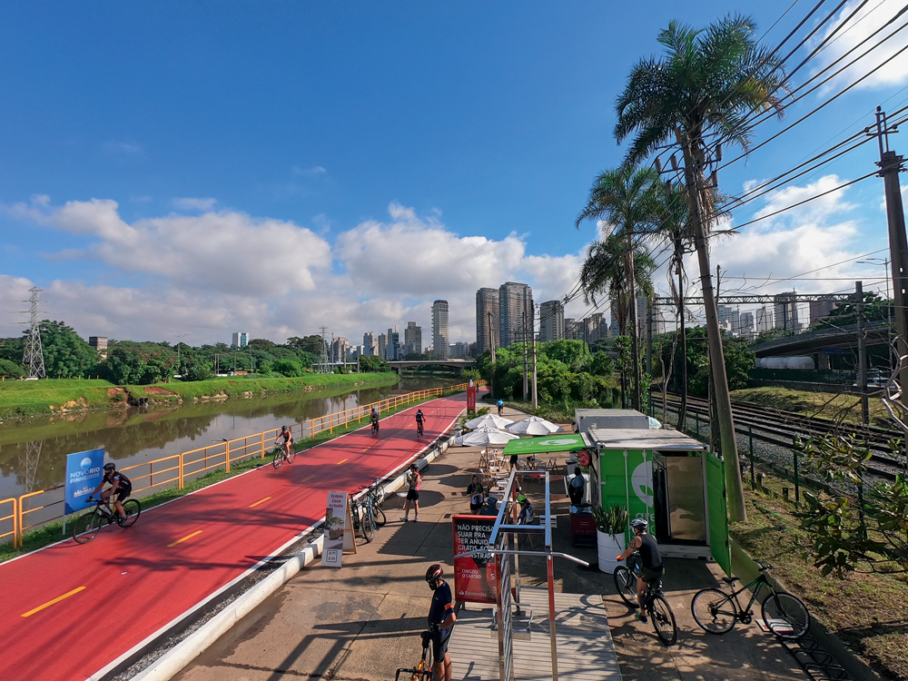 DCIM100GOPROG0070200.JPG Imagem vista de cima da ciclo faixa do Rio Pinheiros. Há ciclistas de capacete utilizando a pista em um dia com céu azul com apenas nuvens ao fundo