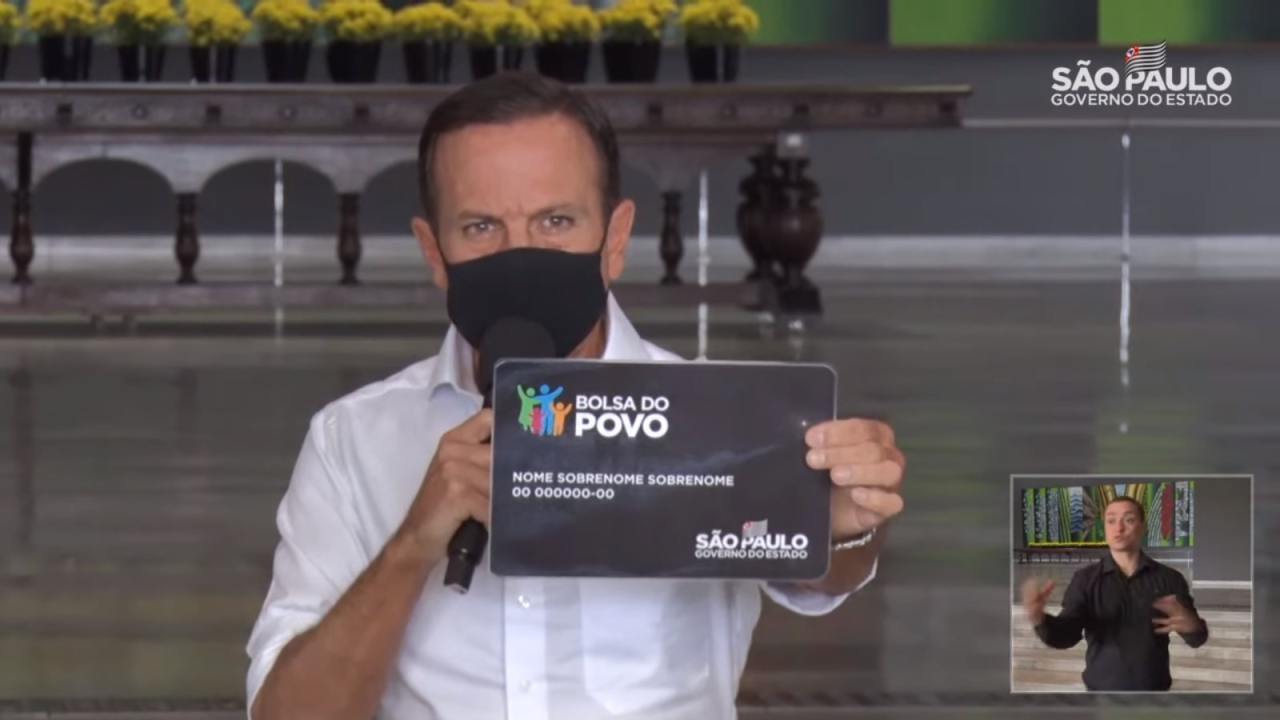 governador Doria segurando réplica em tamanho aumentado de cartão do programa bolsa do povo