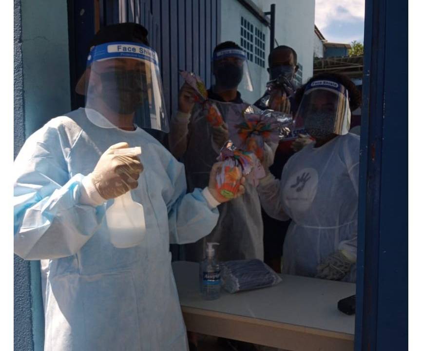 Membros do instituto equipados com diversas proteções, influindo facemask, para evitar o contágio pela Covid-19. A pessoa na frente segura um borrifador e um ovo de chocolate embalada