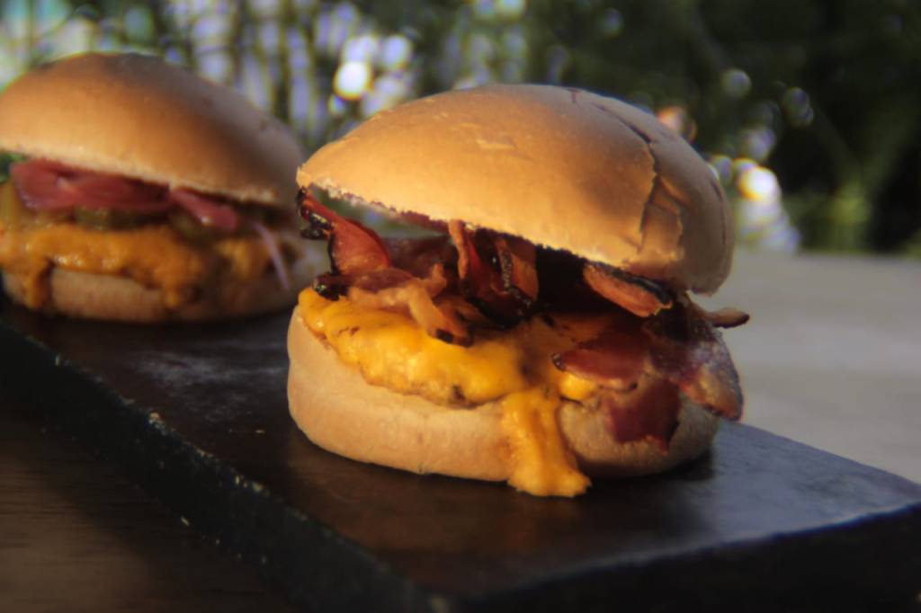 Obra Burguer Em primeiro plano, sanduíche feito com pão, hambúrguer, queijo e bacon