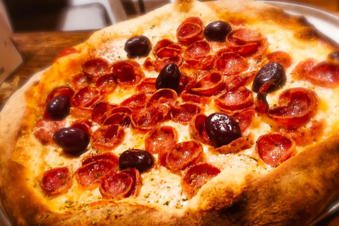 Pizza com cobertura de muçarela e calabresa, com algumas azeitonas pretas