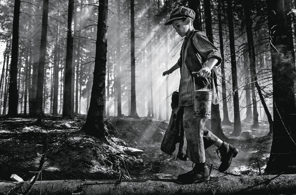 opassaro.jpg Petr Kotlár, em uma imagem preta e branca, anda com roupas tradicionais do leste europeu da época da ll Guerra. Ele está em meio a uma floresta.