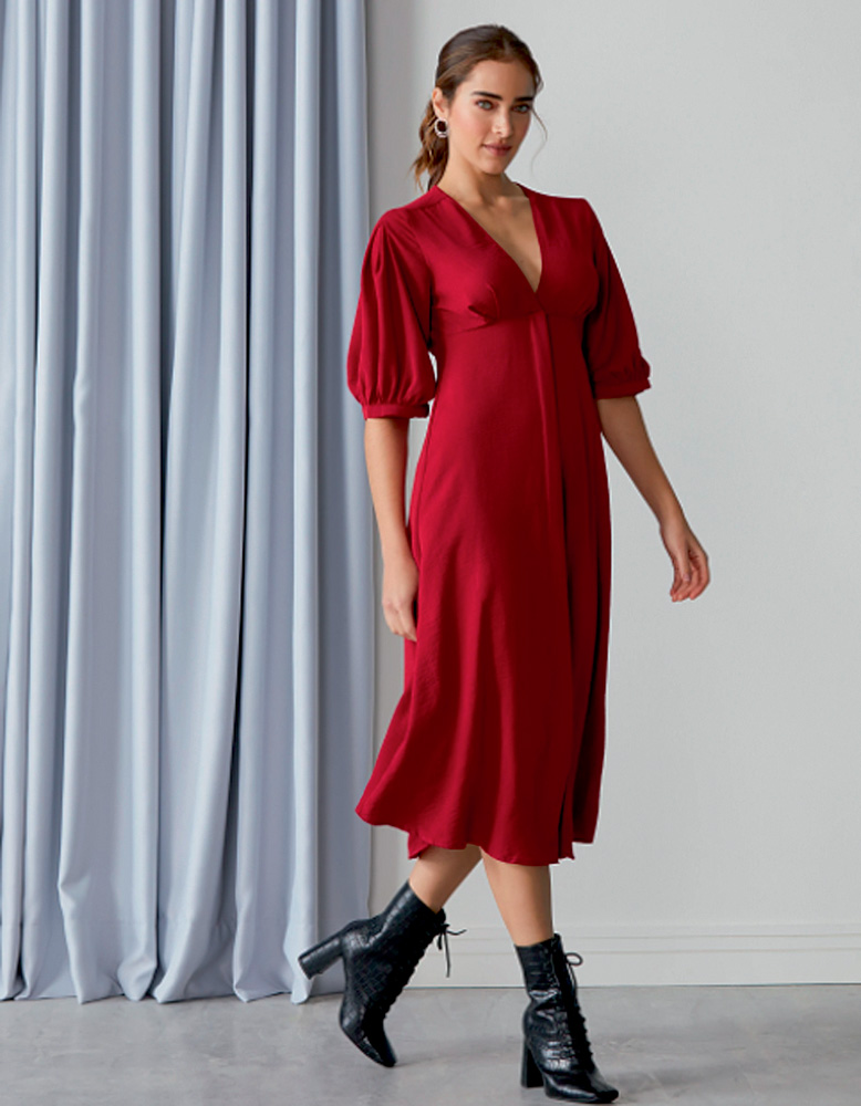 Mulher caminha com vestido vermelho olhando para c&acirc;mera