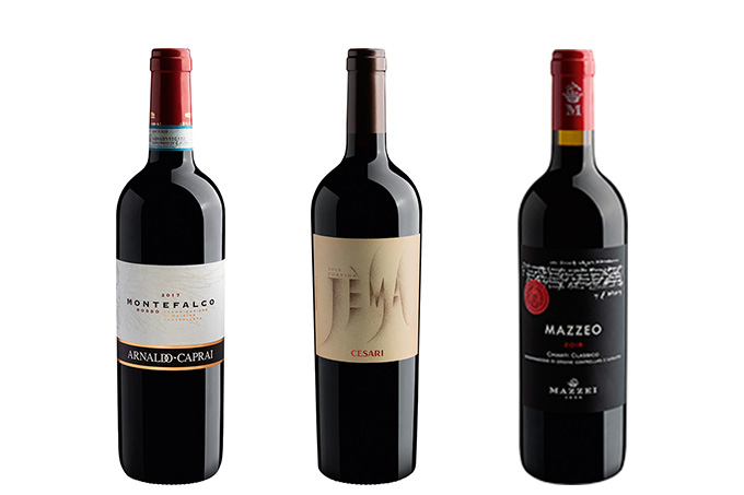 Três garrafas de vinho tinto seguidas, rótulos podem ser encontrados na Evino
