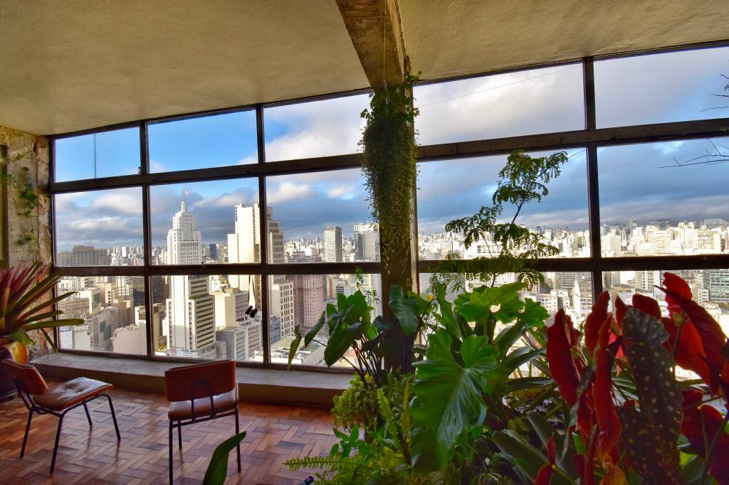 Andar 43 – Foto André Gomes – @andredvco – maio 2021 – 4 Imagem mostra sala com vista para o centro da cidade com plantas e cadeira no centro
