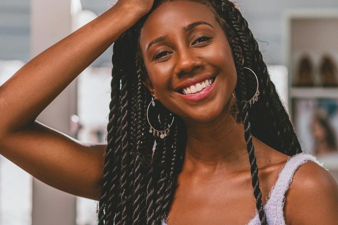 A imagem mostra Camilla de Lucas posando para foto com a mão na cabeça e sorrindo de forma descontraída