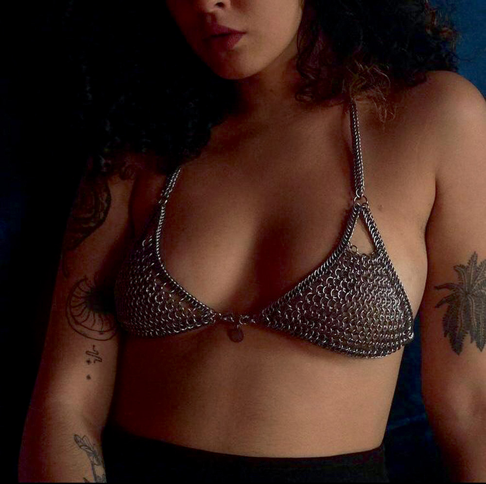 Créditos_Divulgação.jpg Foto mostra do nariz para baixo de uma mulher até sua cintura. Ela veste um top feito de argolas metálicas