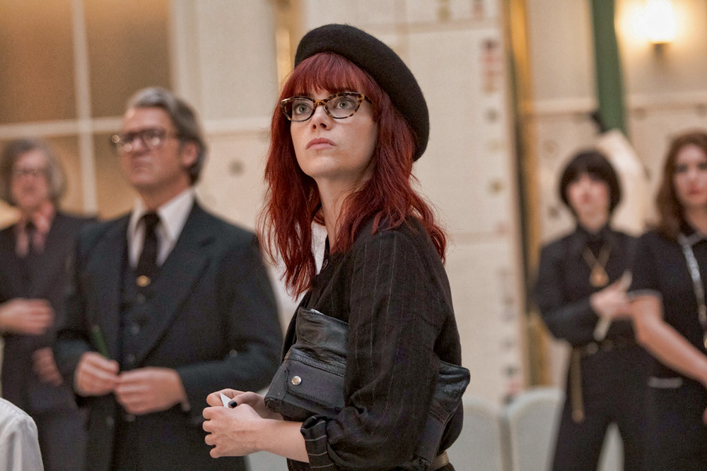 A imagem mostra Emma Stone, de boina e cabelo ruivo, olhando para cima em cena de Cruella