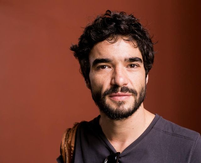 caio blat com um meio sorriso olhando para a câmera