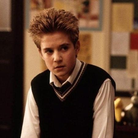 kevin clark Imagem mostra Kevin Clark caracterizado como Freddy Spazzy McGee no filme 'Escola de Rock', aparece usando colete e camiseta, dentro de sala de aula
