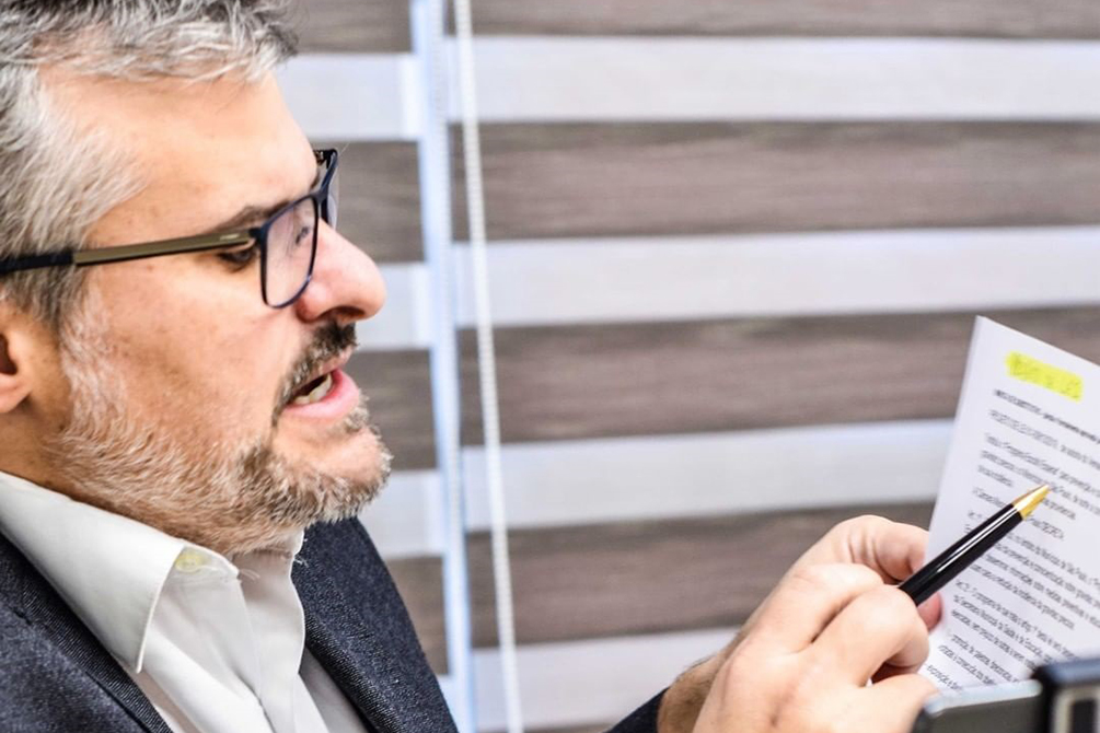 Imagem mostra o vereador segurando folha de papel, em que o texto do projeto de lei está escrito, enquanto aponta trecho grifado com uma caneta
