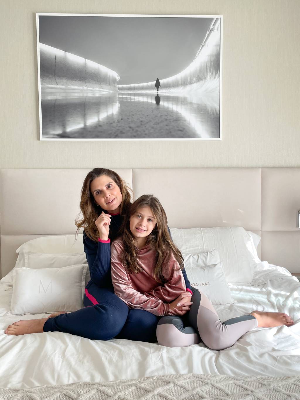 Mari e Vicky – Mariana Kupfer e a filha posam com fotografia produzida por Aryanne Valgas (DIVULGAÇÃO) Mariana Kupfer e a filha Vicky posam sentadas na cama branca com fotografia produzida por Aryanne Valgas.