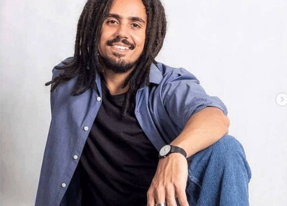 felipe macalé sentado posando para a foto, com um dos braços apoiado em joelho