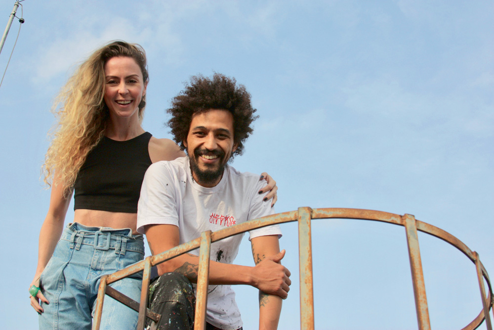 Fernanda-Pagú-mostra-grafites-minhocão.jpg casal fernanda de pagu posando para a foto em cima de uma superfície com corrimão olhando para baixo