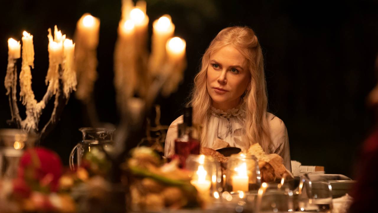 A imagem mostra uma mulher com expressão séria em uma mesa de jantar