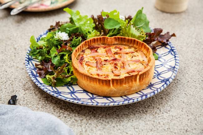 Gansaral Torta de chucrute com parte superior de bacon trançado ao lado de salada de alface.