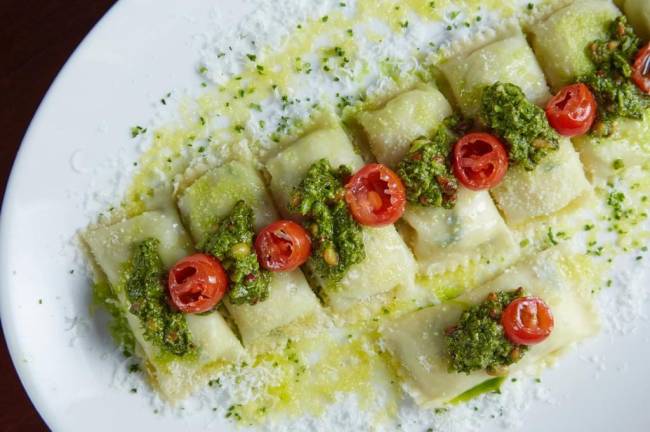 Moma Modern Mamma Osteria Massa do Moma Modern Mamma Osteria de formato cilíndrico coberta por pesto e tomatinho.