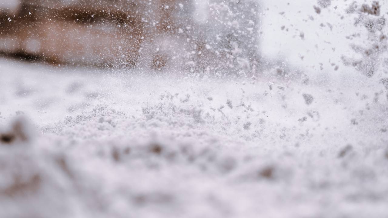 Imagem registrada perto do chão mostra flocos de neve caindo e acumulados