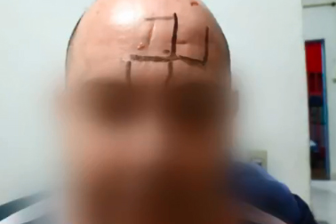 Imagem mostra homem careca, com rosto borrado: suástica desenhada com caneta aparece na região da testa