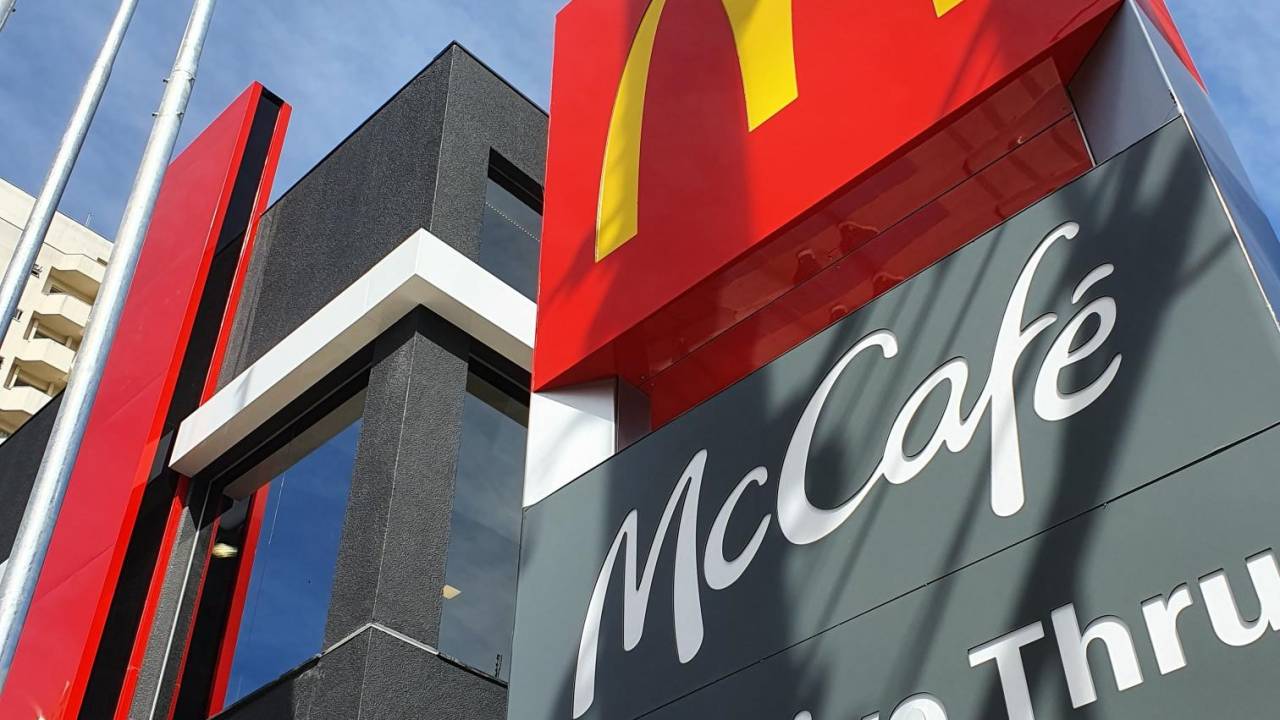 Logotipo do McCafé e McDonald's aparece na foto ao lado de bandeira do Brasil.