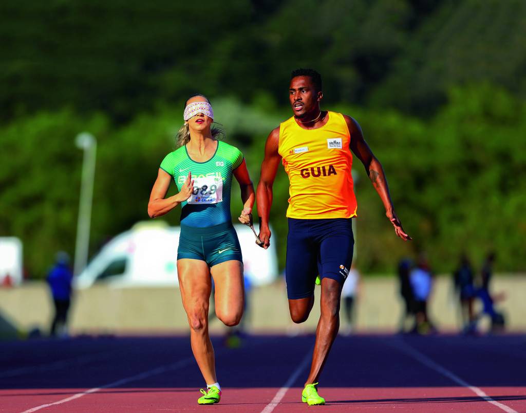 Desafio CBAt/CPB 2019 – ©Wagner Carmo/CPB/Exemplus Uma atleta com uma venda no rosto corre na pista com seu guia
