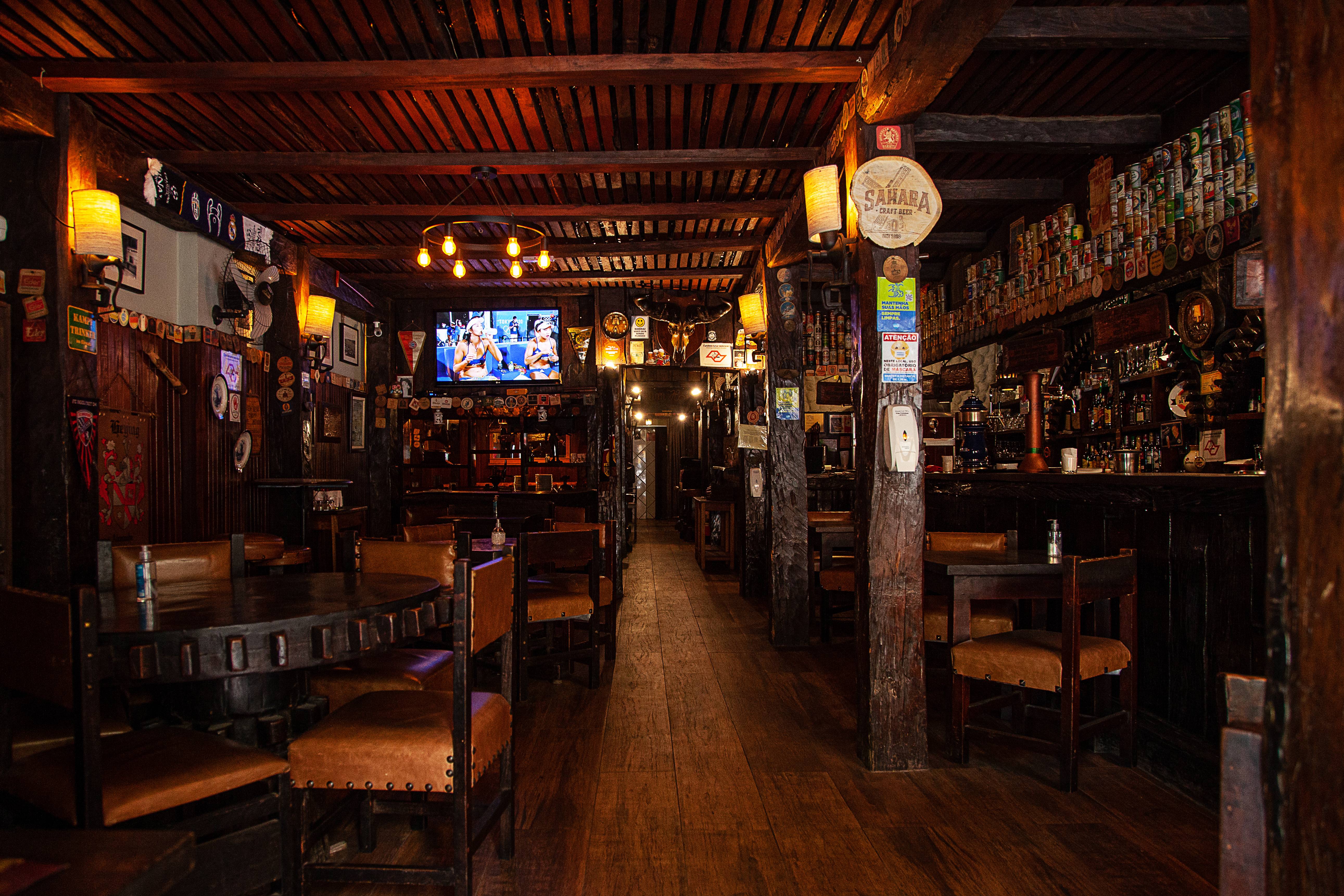 Sal&atilde;o do bar Zur Alten M&uuml;hle com paredes de madeira cobertas por bolachas de chope e mesas de madeira com cadeiras com estofaos de couro.