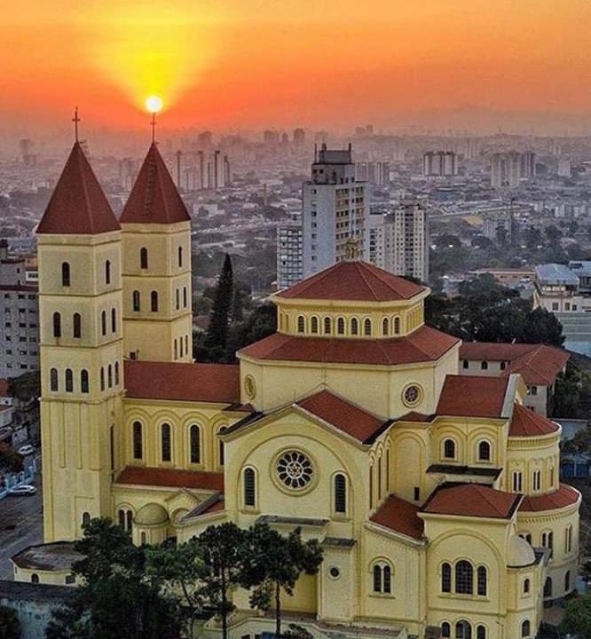 foto da basílica de nossa senhora da penha com sol poente ao fundo e bairro da penha abaixo da basílica