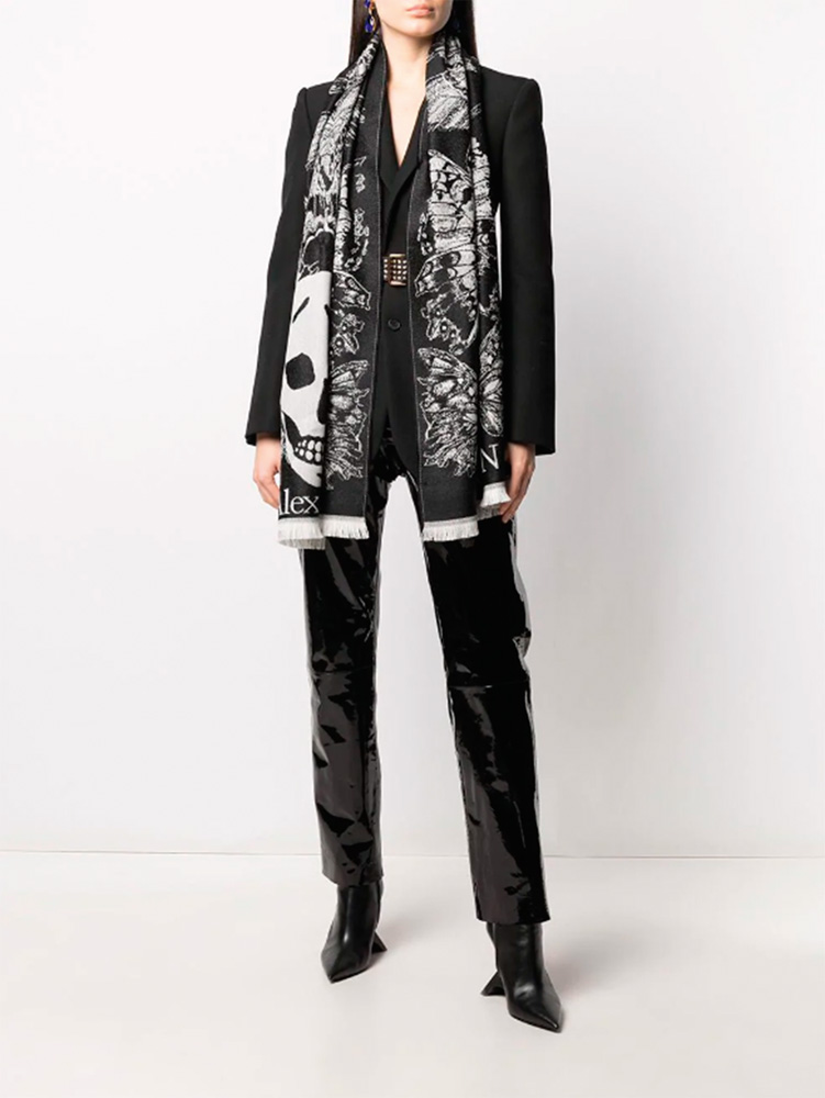 echarpe alexander mcqueen.png Imagem mostra só corpo de mulher vestindo preto e um echarpe preto e branco com estampa de caveiras