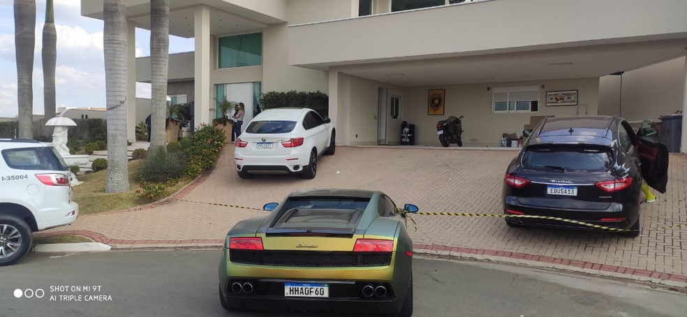 A imagem mostra carros de luxo em frente à residência
