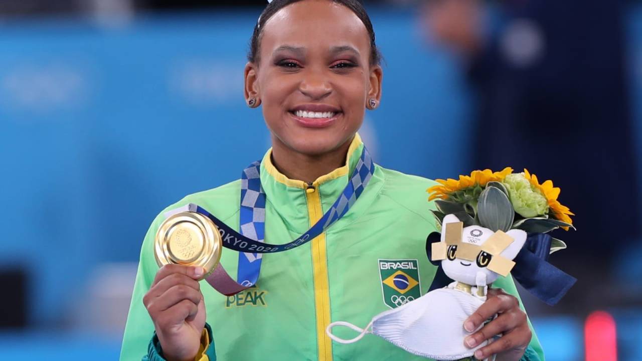 A imagem mostra Rebeca segurando a medalha de ouro no pódio