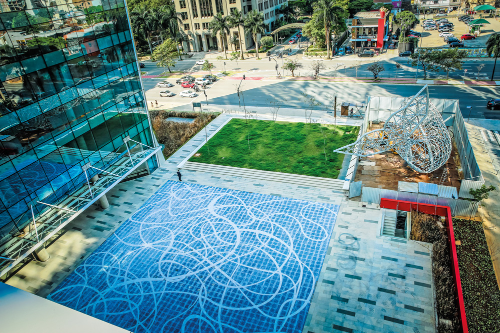 A imagem mostra a fachada do novo prédio de luxo. Há um grande espaço no térreo azul com desenho de fios brancos sobre ele.