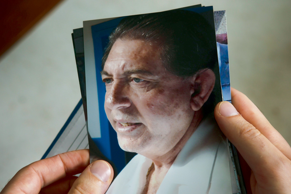 A imagem mostra uma mão segurando uma foto de João de Deus.