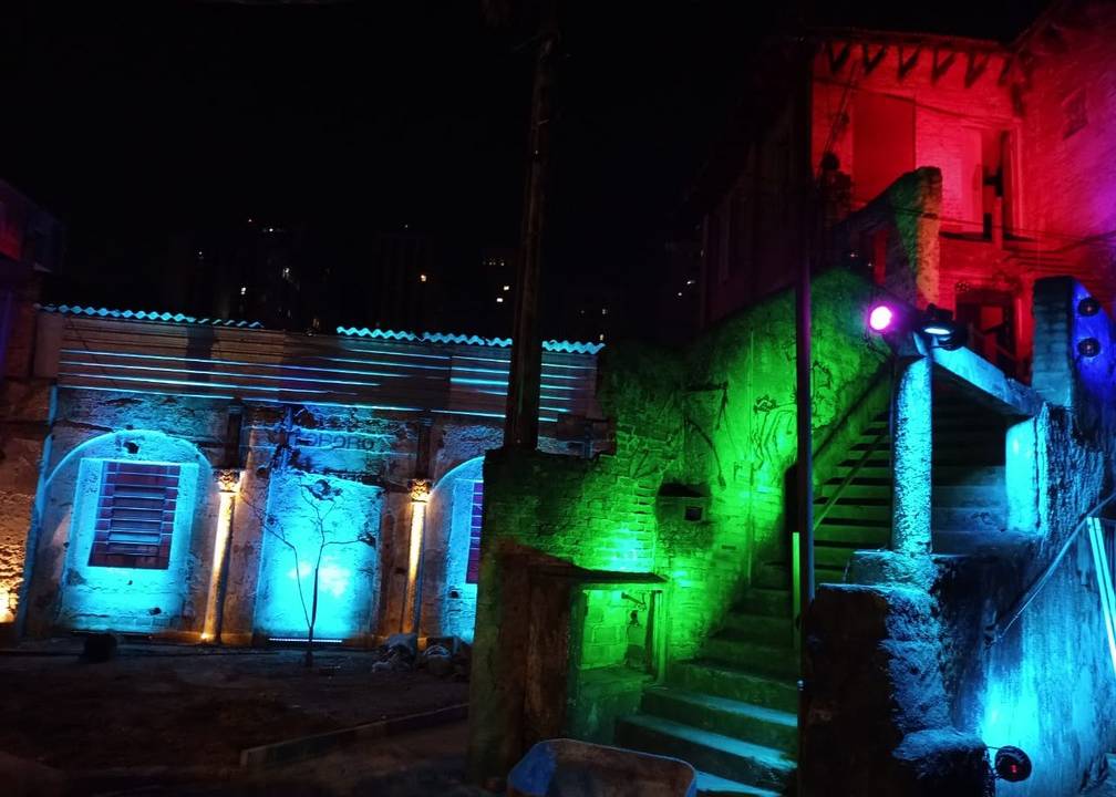 A imagem mostra uma escada na Vila Itororó com uma iluminação colorida durante a noite.
