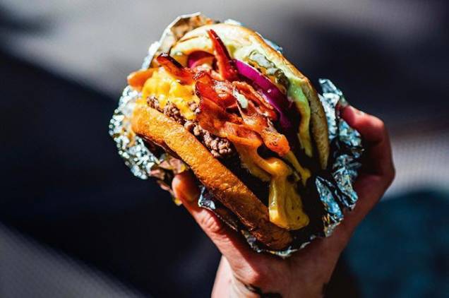 Jota jota: com queijo americano, tiras de bacon, cebola-roxa, picles de pepino e maionese Jota jota: com queijo americano, tiras de bacon, cebola-roxa, picles de pepino e maionese