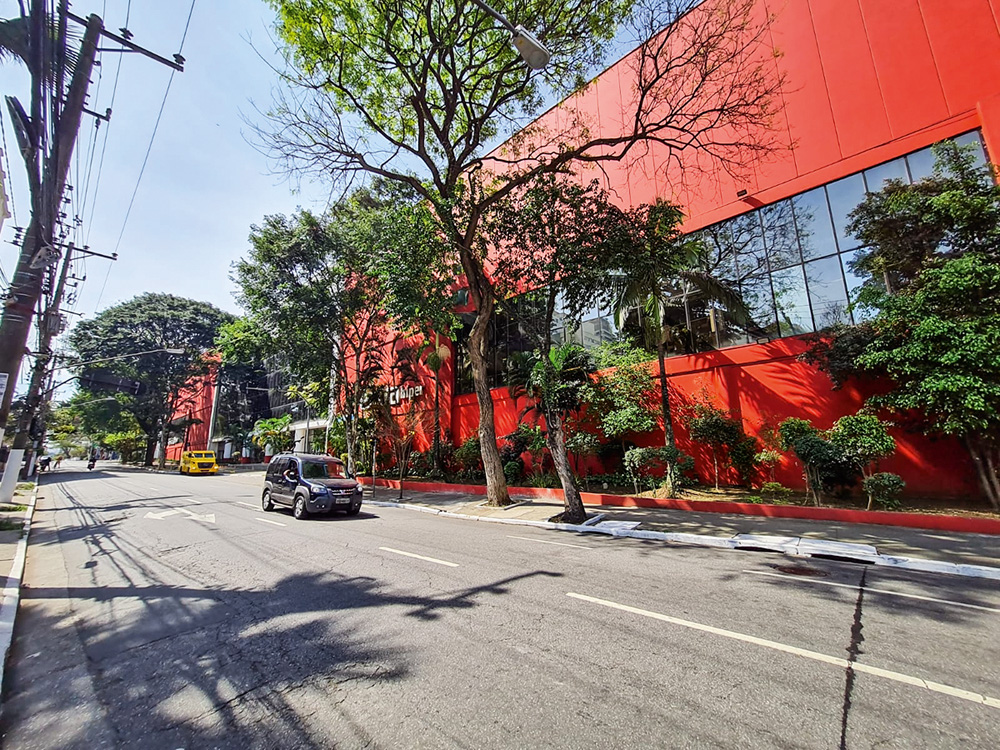 O Extra da João Cachoeira Foto mostra parte lateral do supermercado Extra, pintado todo de vermelho com janelas de vidro. Algumas árvores ao redor