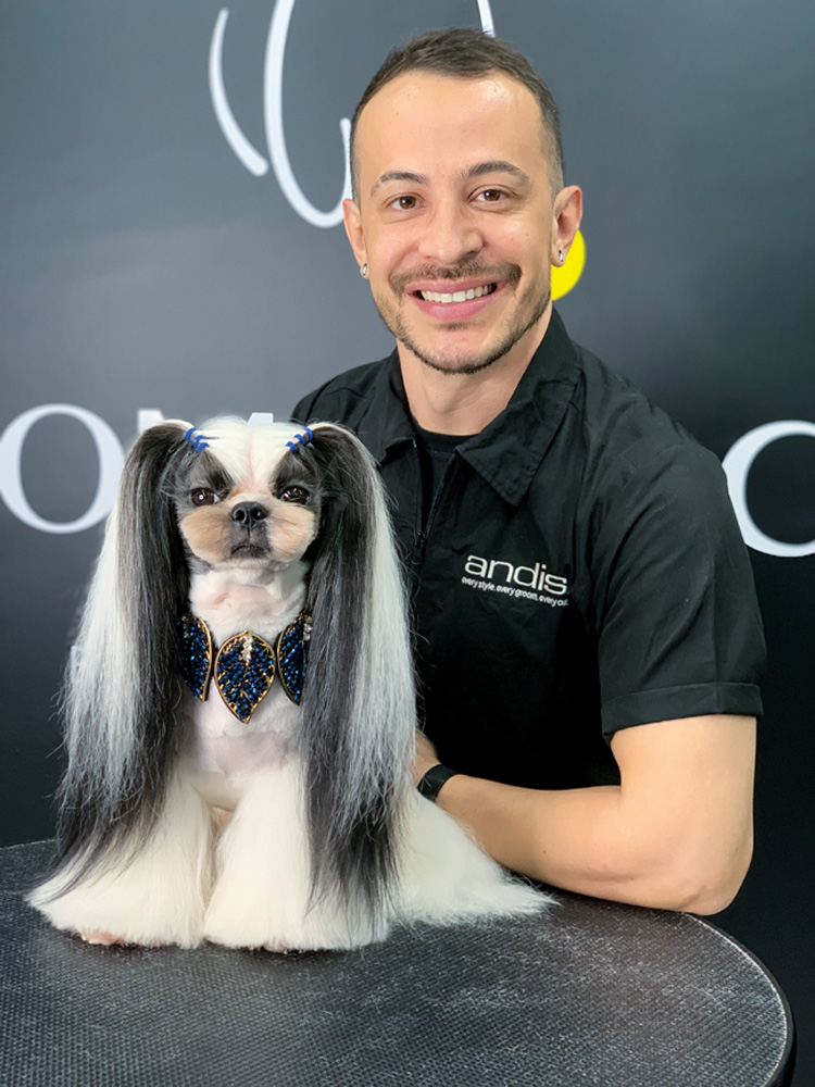 luiz-renato-grooming-care-cachorro-groomers.jpg Luiz Renato segurando um cachorro que ele acabou de estilizar o pelo. o cachorro, em cima da mesa, tem mais pelo perto das extremidades das patas e o pelo das orelhas está grande