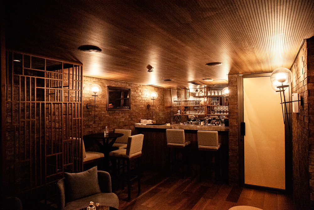 Ambiente do bar decorado com mesas e cadeiras altas e um balcão