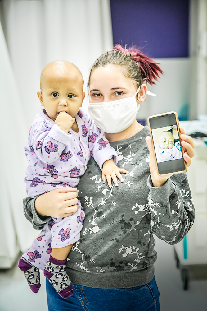 São Paulo 21 outubro 2021GRAACCFoto Alexandre Battibugli Veja SP A imagem mostra Rita de Cássia segurando sua filha criança Anna Laura. Na mão, um celular mostrando a foto da filha antes do tratamento.