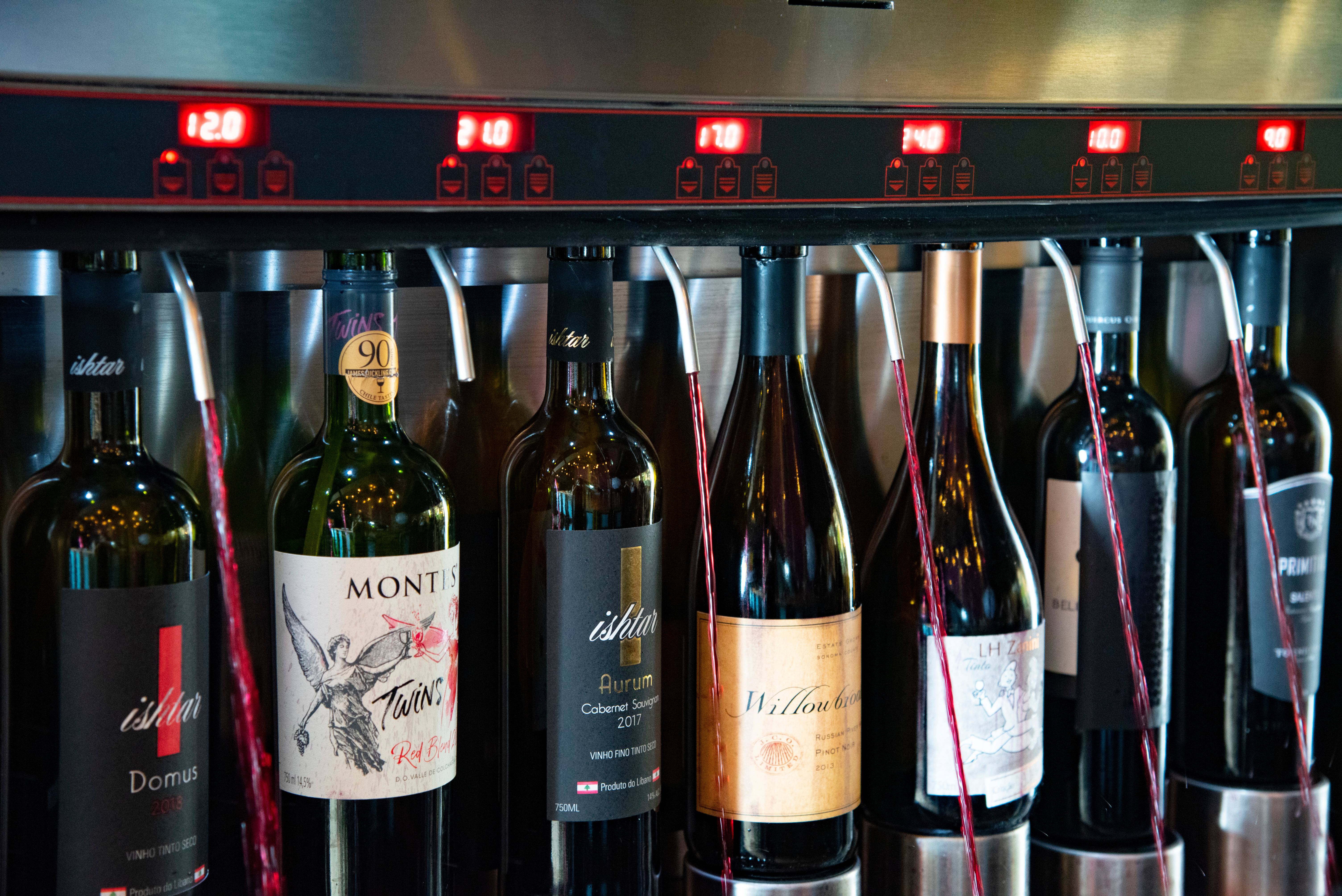 Garrafas de vinho acompladas &agrave; maquina com torneiras soltando vinhos tintos.