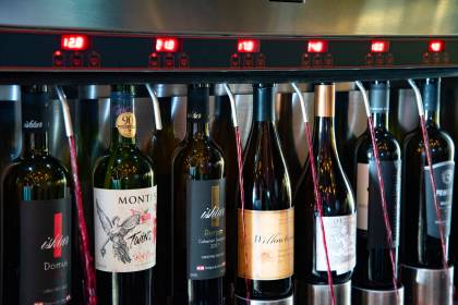 Comer & Beber 2021 - Bardega Garrafas de vinho acompladas à maquina com torneiras soltando vinhos tintos.