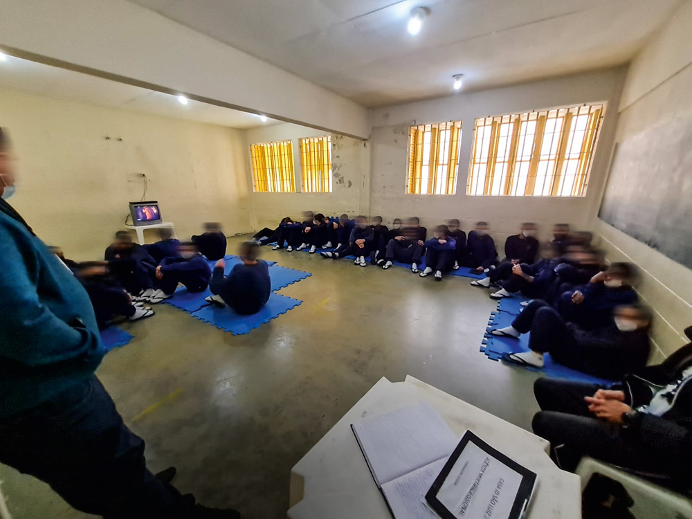 Fundação Casa Jovens vendo televisão A imagem mostra jovens sentados em tatames em volta de uma televisão pequena.