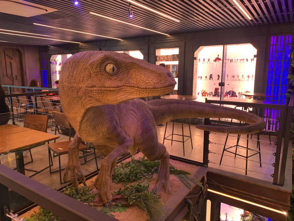 Jurassic Park Burger Restaurant Réplica de um velociraptor olhando para o lado sobre suporte.