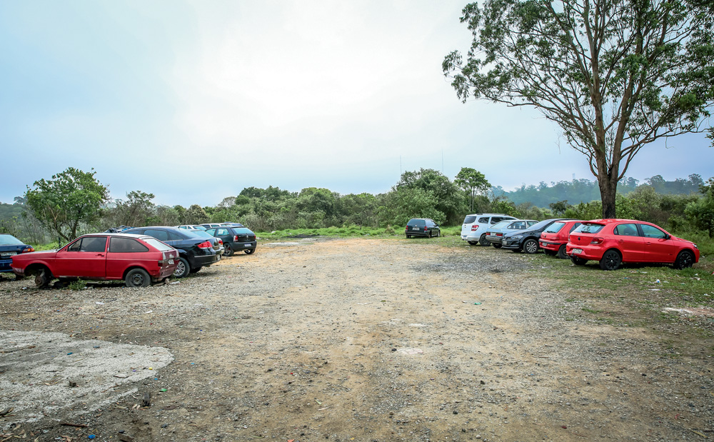 JDAPURA_15.JPG Um estacionamento sem asfalto, com alguns carros nos lados e, ao fundo, uma mata