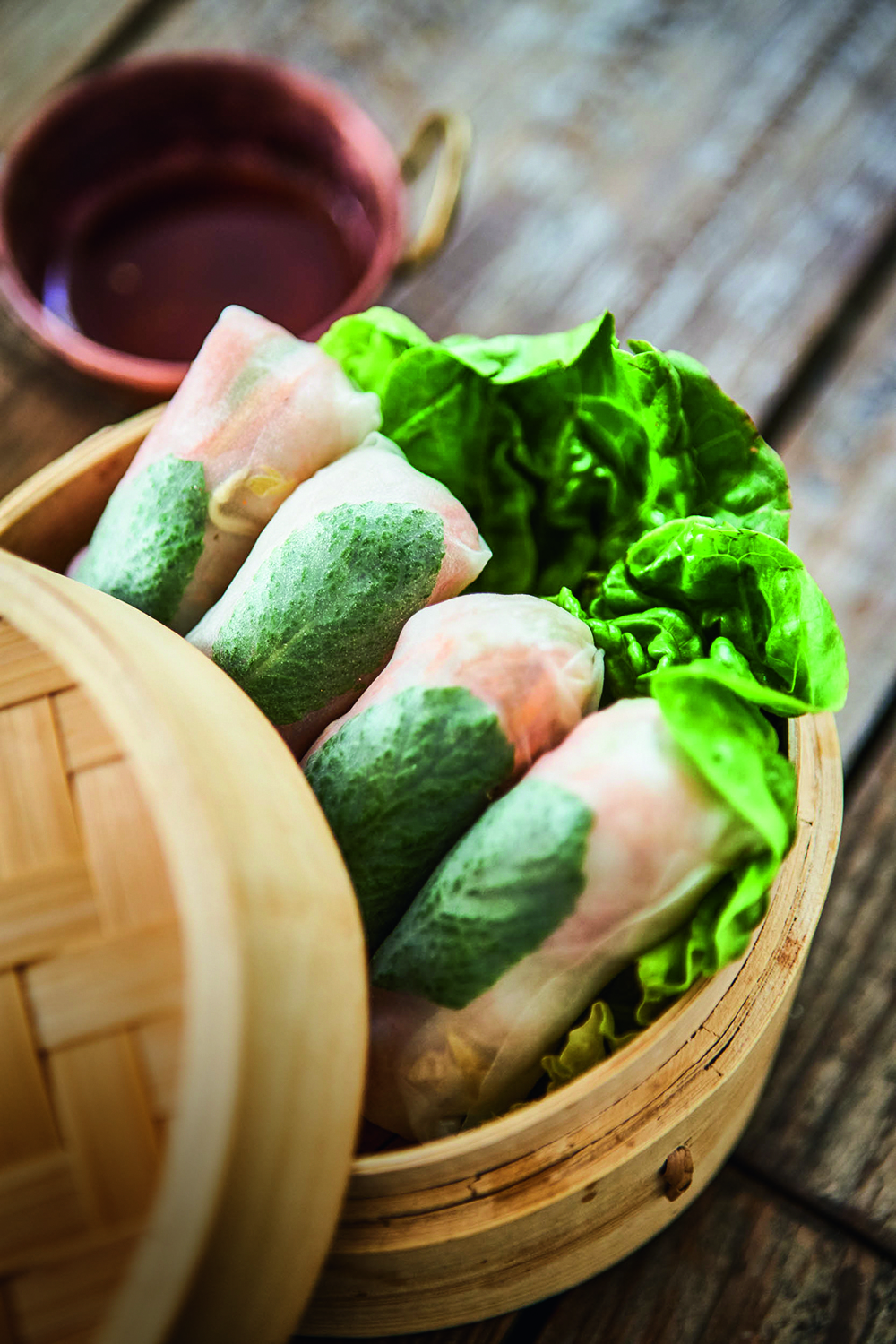 Rolinhos no papel de arroz dentro de cesta de palha forrada por alface.