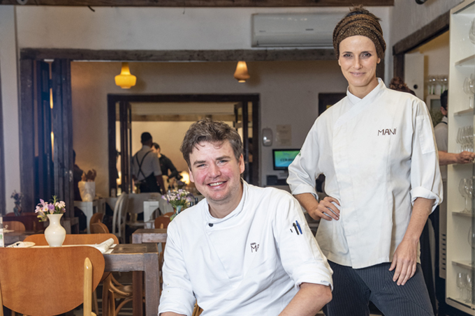 Os chefs Willem Vandevem sentado (à esquerda) e Helena Rizzo em pé (à direita) no salão do Maní.