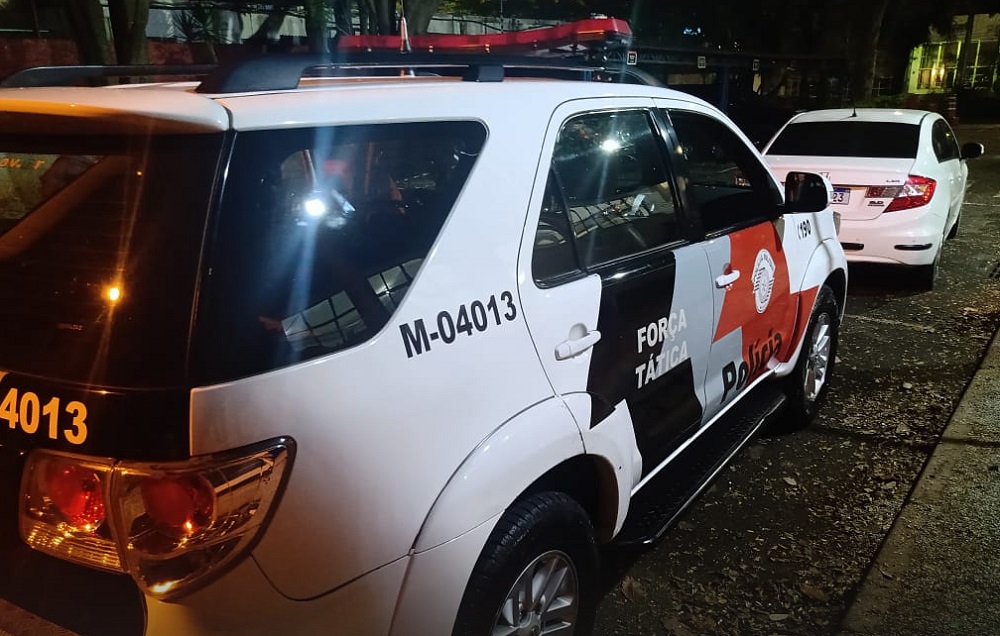 Imagem mostra viatura da Polícia Militar parada atrás de carro usado pelos criminosos
